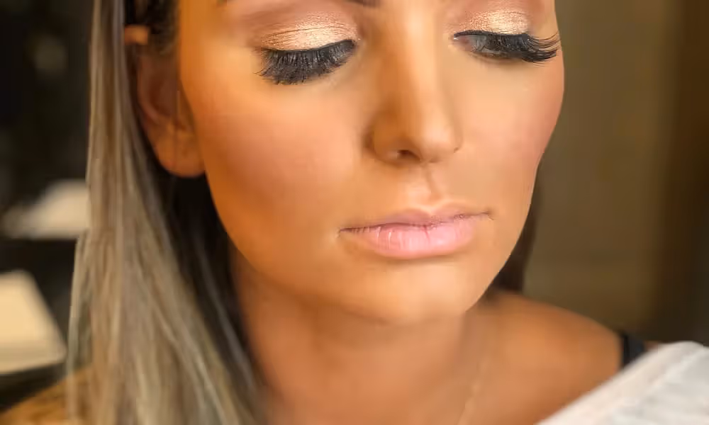 Woman looks downward to show off golden eyeshadow 